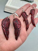 Load image into Gallery viewer, Red angel wings earrings made of polymer clay. These earrings are designed to face forward when worn instead of the front wings showing on the side.