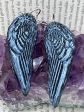 Load image into Gallery viewer, Shimmery silver color angel wings earrings made of polymer clay. These earrings are designed to face forward when worn instead of the front wings showing on the side.