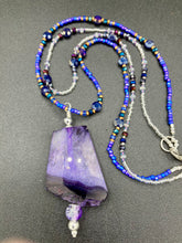 Load image into Gallery viewer, For The Love Of Nature - Vibrant Purple Agate Nature Stone With Two Strands of Multi-Color Glass Beaded Necklace. Large agate stone is full of purple hues from sheer, to vibrant violet, to deep dark purples. This beautiful agate necklace is the perfect summer necklace. Measurements: Necklace is 15 1/2” adjustable up to 18" in length - pendant is 2 1/2” Height