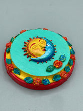 Load image into Gallery viewer, Handcrafted polymer clay wall art with a wood frame, featuring a sun and moon motif complemented with contrasting cool and warm colors. The background is a bright turquoise hue, with marigold flowers and leaves adorning the frame.Measurement 4" diameter