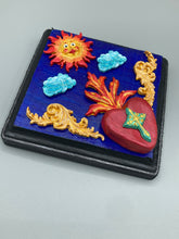 Load image into Gallery viewer, This handcrafted polymer clay wall art is displayed on a square wood frame, featuring sun and light blue cloud motifs on each side and a dark royal blue backdrop with a bright red sacred heart in the center. A turquoise and yellow cross provides contrast to the warm toned heart, which is further embellished with gold accents on each side of the heart. H 6 3/4" x W 6 3/4” x D 1"