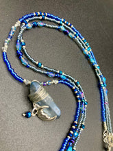 Load image into Gallery viewer, This jewelry piece is a delicate harmony of light and dark tones. Three strands feature a mix of navy blue, pewter, and oval-shaped, light blue-gray beads with a subtle iridescence of amethyst, emerald, and gold. Its celestial theme and bold composition create an alluringly elegant accessory. This whimsical necklace boasts a wonderfully unique aesthetic, featuring a wired blue luster nugget and a whimsical crescent moon charm. Measurements: Necklace is 15 1/4”adjustable up to 18"