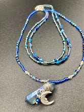 Load image into Gallery viewer, This jewelry piece is a delicate harmony of light and dark tones. Three strands feature a mix of navy blue, pewter, and oval-shaped, light blue-gray beads with a subtle iridescence of amethyst, emerald, and gold. Its celestial theme and bold composition create an alluringly elegant accessory. This whimsical necklace boasts a wonderfully unique aesthetic, featuring a wired blue luster nugget and a whimsical crescent moon charm. Measurements: Necklace is 15 1/4”adjustable up to 18"