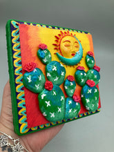 Load image into Gallery viewer, This handcrafted polymer clay wall art boasts a square-shaped wood frame with a sun and crescent moon motifs. Its warm sky hues, including yellow, orange and dark red, are further complemented by hand sculpted cacti plants with cool green-blue tones and dark pink flowers. The dark green frame adds an extra layer of sophistication to the warm-toned artwork. One of a kind art pieces come ready to hang with a sawtooth hangers in the back. H 5" x W 5” x D 1 1/2"H 5" x W 5” x D 1 1/2"