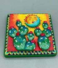 Load image into Gallery viewer, This handcrafted polymer clay wall art boasts a square-shaped wood frame with a sun and crescent moon motifs. Its warm sky hues, including yellow, orange and dark red, are further complemented by hand sculpted cacti plants with cool green-blue tones and dark pink flowers. The dark green frame adds an extra layer of sophistication to the warm-toned artwork. One of a kind art pieces come ready to hang with a sawtooth hangers in the back. H 5" x W 5” x D 1 1/2"H 5" x W 5” x D 1 1/2"