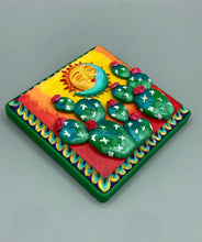 Load image into Gallery viewer, This handcrafted polymer clay wall art boasts a square-shaped wood frame with a sun and crescent moon motifs. Its warm sky hues, including yellow, orange and dark red, are further complemented by hand sculpted cacti plants with cool green-blue tones and dark pink flowers. The dark green frame adds an extra layer of sophistication to the warm-toned artwork. One of a kind art pieces come ready to hang with a sawtooth hangers in the back. H 5" x W 5” x D 1 1/2"H 5" x W 5” x D 1 1/2"