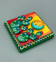 Load image into Gallery viewer, This handcrafted polymer clay wall art boasts a square-shaped wood frame with a sun and crescent moon motifs. Its warm sky hues, including yellow, orange and dark red, are further complemented by hand sculpted cacti plants with cool green-blue tones and dark pink flowers. The dark green frame adds an extra layer of sophistication to the warm-toned artwork. One of a kind art pieces come ready to hang with a sawtooth hangers in the back. H 5" x W 5” x D 1 1/2"H 5" x W 5” x D 1 1/2"
