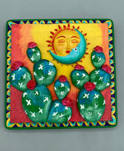 Load image into Gallery viewer, This handcrafted polymer clay wall art boasts a square-shaped wood frame with a sun and crescent moon motifs. Its warm sky hues, including yellow, orange and dark red, are further complemented by hand sculpted cacti plants with cool green-blue tones and dark pink flowers. The dark green frame adds an extra layer of sophistication to the warm-toned artwork. One of a kind art pieces come ready to hang with a sawtooth hangers in the back. H 5" x W 5” x D 1 1/2"H 5" x W 5” x D 1 1/2"