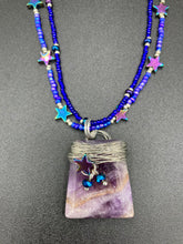 Load image into Gallery viewer, This elegant amethyst trapezoid pendant is artfully wirewrapped with a hematite star bead, making this a unique piece perfect for any occasion. Its two strands of colorful glass beads in a mix of cool blues, purples, and silver create an enchanting, starry night look sure to make a statement. Necklace is 16” in length and can be adjusted to 18"