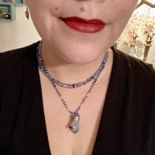 Load image into Gallery viewer, This jewelry piece is a delicate harmony of light and dark tones. Three strands feature a mix of navy blue, pewter, and oval-shaped, light blue-gray beads with a subtle iridescence of amethyst, emerald, and gold. Its celestial theme and bold composition create an alluringly elegant accessory. This whimsical necklace boasts a wonderfully unique aesthetic, featuring a wired blue luster nugget and a whimsical crescent moon charm. Measurements: Necklace is 15 1/4”adjustable up to 18"