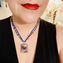 Load image into Gallery viewer, This elegant amethyst trapezoid pendant is artfully wirewrapped with a hematite star bead, making this a unique piece perfect for any occasion. Its two strands of colorful glass beads in a mix of cool blues, purples, and silver create an enchanting, starry night look sure to make a statement. Necklace is 16” in length and can be adjusted to 18"