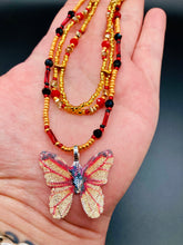 Load image into Gallery viewer, This intricately crafted pendant features a Basil leaf molded in Sterling Silver and adorned with stunningly vivid red, gold, and black glass beaded necklace. Its eye-catching butterfly design adds a bold, yet whimsical touch, making it an ideal choice for a summer look. Necklace is 15 1/2” in length adjustable to 18"