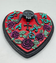 Load image into Gallery viewer, This Memento Mori Wall Art Decor is a one-of-a-kind art piece, skillfully crafted with a black polymer clay skull and wings on a dark red wood frame, decoratively woven with dark red roses and vines. It's perfect for adding an eye-catching touch to any wall and makes a unique, bold gift. Measurements: H 6 3/4" x W 7” x D 1 1/2"