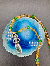 Load image into Gallery viewer, "Amaterasu" Japanese Goddess of the Sun. Necklace is primarily vibrant yellow glass beads that are full of color and shimmer to represent the bright sun. Added a wide range of shimmers of gold and orange and different shades of yellow. Larger green glass beads with small gold beads to really stand out and give the necklace a different dimension and feel. This vibrant goddess necklace is the perfect pop of color to any outfit. Necklace is 16 1/2” adjustable to 19" - pendant is nickel free 1 1/2”