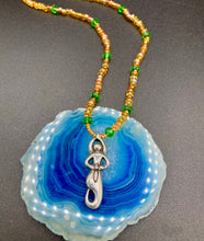 Load image into Gallery viewer, "Amaterasu" Japanese Goddess of the Sun. Necklace is primarily vibrant yellow glass beads that are full of color and shimmer to represent the bright sun. Added a wide range of shimmers of gold and orange and different shades of yellow. Larger green glass beads with small gold beads to really stand out and give the necklace a different dimension and feel. This vibrant goddess necklace is the perfect pop of color to any outfit. Necklace is 16 1/2” adjustable to 19" - pendant is nickel free 1 1/2”