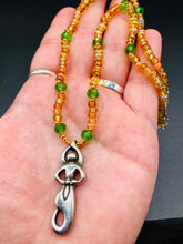 Load image into Gallery viewer, "Amaterasu" Japanese Goddess of the Sun. Necklace is primarily vibrant yellow glass beads that are full of color and shimmer to represent the bright sun. Added a wide range of shimmers of gold and orange and different shades of yellow. Larger green glass beads with small gold beads to really stand out and give the necklace a different dimension and feel. This vibrant goddess necklace is the perfect pop of color to any outfit. Necklace is 16 1/2” adjustable to 19" - pendant is nickel free 1 1/2”