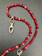 Load image into Gallery viewer, "Aphrodite" - the Ancient Greek goddess of love and beauty! Goddess pendant with a heart shaped feature represents love and beauty. The primary glass beads are of a vibrant red but every bead has a wide range of shimmers of gold and slightly different shades of red. Larger dark red glass beads stand out and give the necklace a different dimension and feel. Comes with matching rings and is the perfect pop of color to any outfit. Necklace is 17” adjustable to 19" - pendant is nickel free and 1 1/2”