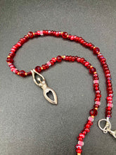 Load image into Gallery viewer, "Aphrodite" - the Ancient Greek goddess of love and beauty! Goddess pendant with a heart shaped feature represents love and beauty. The primary glass beads are of a vibrant red but every bead has a wide range of shimmers of gold and slightly different shades of red. Larger dark red glass beads stand out and give the necklace a different dimension and feel. Comes with matching rings and is the perfect pop of color to any outfit. Necklace is 17” adjustable to 19" - pendant is nickel free and 1 1/2”