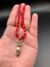 Load image into Gallery viewer, "Aphrodite" - the Ancient Greek goddess of love and beauty! Goddess pendant with a heart shaped feature represents love and beauty. The primary glass beads are of a vibrant red but every bead has a wide range of shimmers of gold and slightly different shades of red. Larger dark red glass beads stand out and give the necklace a different dimension and feel. Comes with matching rings and is the perfect pop of color to any outfit. Necklace is 17” adjustable to 19" - pendant is nickel free and 1 1/2”