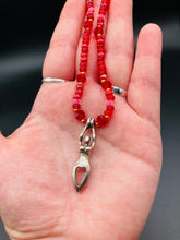 Load image into Gallery viewer, "Aphrodite" - the Ancient Greek goddess of love and beauty! Goddess pendant with a heart shaped feature represents love and beauty. The primary glass beads are of a vibrant red but every bead has a wide range of shimmers of gold and slightly different shades of red. Larger dark red glass beads stand out and give the necklace a different dimension and feel. Comes with matching rings and is the perfect pop of color to any outfit. Necklace is 17” adjustable to 19" - pendant is nickel free and 1 1/2”