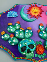Load image into Gallery viewer, This handcrafted polymer clay wall art features a wood frame painted in a gradient from light pink to dark purple, creating a stunning sunset look. With two bright green skull cactus plant and bright yellow orange blooming flowers. Featuring a vivid sun and crescent moon with a backdrop of dark blue clouds, this frame is sure to make an impression. A bight teal and yellow hue frame to make a bold contrast with the warm background hue. This piece is sure to make a statement.