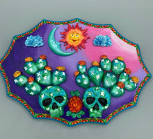 Load image into Gallery viewer, This handcrafted polymer clay wall art features a wood frame painted in a gradient from light pink to dark purple, creating a stunning sunset look. With two bright green skull cactus plant and bright yellow orange blooming flowers. Featuring a vivid sun and crescent moon with a backdrop of dark blue clouds, this frame is sure to make an impression. A bight teal and yellow hue frame to make a bold contrast with the warm background hue. This piece is sure to make a statement.
