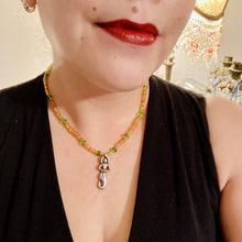 Load image into Gallery viewer, "Amaterasu" Japanese Goddess of the Sun. Necklace is primarily vibrant yellow glass beads that are full of color and shimmer to represent the bright sun. Added a wide range of shimmers of gold and orange and different shades of yellow. Larger green glass beads with small gold beads to really stand out and give the necklace a different dimension and feel. This vibrant goddess necklace is the perfect pop of color to any outfit. Necklace is 16 1/2” adjustable to 19" - pendant is nickel free 1 1/2”