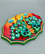 Load image into Gallery viewer, This handcrafted polymer clay wall art features a wood frame painted in a gradient from light yellow to dark red, creating a stunning sunset look. With two bright green skull cactus plant and bright dark red blooming flowers. Featuring a vivid sun and crescent moon with a backdrop of light blue clouds, this frame is sure to make an impression. A bight green hue frame to make a bold contrast with the warm background hue. This piece is sure to make a statement.