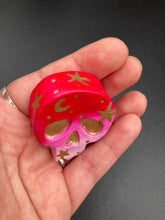 Load image into Gallery viewer, Inspired by nature, this skull statuette is full of vibrant colors and intricate details. The ombre colors from red, to light pink was inspired by the summer sky at sundown that I see all too often. I really wanted to capture those beautiful colors and added metallic gold moon and stars silhouettes to tie it all together.
