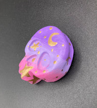 Load image into Gallery viewer, Ideal magnet design to adorn your refrigerator, lockers, workstation, toolbox, or dishwasher. This unique skull statuette features intricate details and vibrant colors, inspired by the summer sky at sundown. Variations in color from purple to light pink simulate the dramatic ombre seen in a setting sun, completed with golden stars and moon silhouettes for a celestial touch. H 1 1/2” x W 1 1/2” x D 3/4”