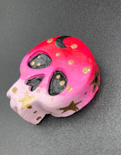 Load image into Gallery viewer, Ideal magnet design to adorn your refrigerator, lockers, workstation, toolbox, or dishwasher. This intricately detailed skull statuette is inspired by the beauty of nature, with vibrant colors ranging from red to a light pink reminiscent of a summer sky at dusk. A black moon and gold stars were added to provide a unified aesthetic. H 1 1/2” x W 1 1/2” x D 3/4”