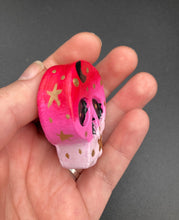 Load image into Gallery viewer, Ideal magnet design to adorn your refrigerator, lockers, workstation, toolbox, or dishwasher. This intricately detailed skull statuette is inspired by the beauty of nature, with vibrant colors ranging from red to a light pink reminiscent of a summer sky at dusk. A black moon and gold stars were added to provide a unified aesthetic. H 1 1/2” x W 1 1/2” x D 3/4”