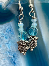 Load image into Gallery viewer, Beautiful delicate glass beaded earrings featuring silver-plated night owl charms in an enchanting pale blue hue. Measurements: 1 1/4” in length