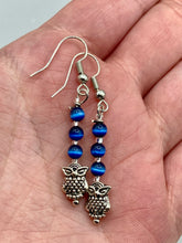 Load image into Gallery viewer, Chic and fun silver-plated owl charm earrings featuring delicate dark blue cats eye beads. Measurements: 1 3/16” in length