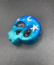 Load image into Gallery viewer, Cute and spooky magnet design to adorn your refrigerator, lockers, workstation, toolbox, or dishwasher. This hand-sculpted clay skull statuette boasts stunning ombre coloration, transitioning from dark blue to light blue to recreate the breathtaking look of a starry night sky. H 1 1/2” x W 1 1/2” x D 3/4”