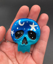 Load image into Gallery viewer, Cute and spooky magnet design to adorn your refrigerator, lockers, workstation, toolbox, or dishwasher. This hand-sculpted clay skull statuette boasts stunning ombre coloration, transitioning from dark blue to light blue to recreate the breathtaking look of a starry night sky. H 1 1/2” x W 1 1/2” x D 3/4”