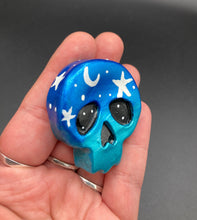 Load image into Gallery viewer, Cute and spooky magnet design to adorn your refrigerator, lockers, workstation, toolbox, or dishwasher. This hand-sculpted clay skull statuette boasts stunning ombre coloration, transitioning from dark blue to light blue to recreate the breathtaking look of a starry night sky. H 1 1/2” x W 1 1/2” x D 3/4”