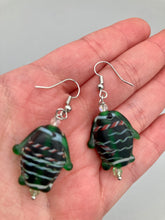 Load image into Gallery viewer, These nature-inspired glass fish earrings are the perfect addition to your boho look. Featuring a delightful dark green hue, the large puffy fish will bring a hippie vibe to your style. Measurements: 1 1/2” in length