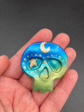 Load image into Gallery viewer, Inspired by nature, this skull statuette is full of vibrant colors and intricate details. The ombre colors from red, to light pink was inspired by the summer sky at sundown that I see all too often. I really wanted to capture those beautiful colors and added metallic gold moon and stars silhouettes to tie it all together.