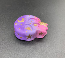 Load image into Gallery viewer, Ideal magnet design to adorn your refrigerator, lockers, workstation, toolbox, or dishwasher. This unique skull statuette features intricate details and vibrant colors, inspired by the summer sky at sundown. Variations in color from purple to light pink simulate the dramatic ombre seen in a setting sun, completed with golden stars and moon silhouettes for a celestial touch. H 1 1/2” x W 1 1/2” x D 3/4”