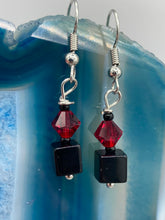 Load image into Gallery viewer, This eye-catching piece features two unconventional components: a large square-shaped black obsidian bead and a large, dark red glass bead. With the beautiful interplay of colors and shapes, these earrings are truly unique, yet at the same time, versatile enough to be paired with a range of styles. Measurements: 1” in length