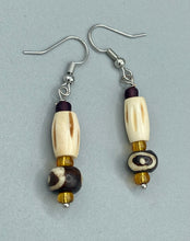Load image into Gallery viewer, This set of earrings features a cylinder bone bead and round bone bead with eye design and a gold-tone glass bead. Neutral colors allow for versatile styling; the resulting look is sure to be unique.  Measurements: 1 1/2 ” in length
