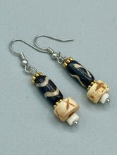 Load image into Gallery viewer, This set of earrings is a one-of-a-kind combination of cylinder and round bone beads with wavy line designs, enhanced with a floral gold tone metal bead set. One earring features vertical wavy lines and crosses, while the other showcases horizontal wavy lines with an "x". The neutral colors make them easy to pair with any ensemble, adding an individualized touch that will make your outfit stand out. Measurements: 1 1/2 ” in length