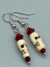 Load image into Gallery viewer, These handcrafted earrings feature a mini-bone carved skull coupled with dark red glass beads. Perfect for Goth, Emo, and Witchy styles, these earrings are sure to provide a unique addition to any Day of the Dead outfit. Our earrings can effortlessly transition between dressy and casual styles. Measurements: 1 1/4 ” in length