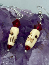 Load image into Gallery viewer, These handcrafted earrings feature a mini-bone carved skull coupled with dark red glass beads. Perfect for Goth, Emo, and Witchy styles, these earrings are sure to provide a unique addition to any Day of the Dead outfit. Our earrings can effortlessly transition between dressy and casual styles. Measurements: 1 1/4 ” in length