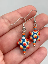 Load image into Gallery viewer, Vibrant color bumpy round lampworked glass bead set of earrings. Colorful teal, white, yellow, and bright orange festive piñata shaped bead.  This also reminds me of the shape of a virus. Either way, this is a super fun, unique, bold piece of jewelry, it's sure to make a statement piece.  Measurements: 1 1/4” in length