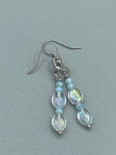 Load image into Gallery viewer, Elevate your style with these simple yet dainty beaded earrings boasting a gentle iridescent and frosty light blue hue. Perfectly versatile, they will add a refined touch to any outfit.  Measurements: 1 1/4” in length