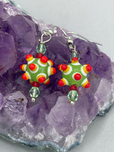 Load image into Gallery viewer, Vibrant, bumpy round lampworked glass beaded earrings in an array of colors including light green, white, yellow, dark red and bright orange. The piñata-shaped bead invokes a festive vibe, while its unique virus-shaped design promotes a bold statement. An eye-catching and unique piece of jewelry sure to turn heads. Measurements: 1 1/4” in length