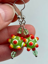 Load image into Gallery viewer, Vibrant, bumpy round lampworked glass beaded earrings in an array of colors including light green, white, yellow, dark red and bright orange. The piñata-shaped bead invokes a festive vibe, while its unique virus-shaped design promotes a bold statement. An eye-catching and unique piece of jewelry sure to turn heads. Measurements: 1 1/4” in length