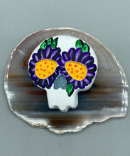 Load image into Gallery viewer, Heal emotionally and spiritually through art by honoring a loved one with a unique and beautiful Purple Spirit Piece Memorial Skull Art. Day Of The Dead Spirit Piece is an ideal addition to your ofrenda or altar that will provide a lasting tribute. These handcrafted polymer clay skull figurines are adorned with hand-painted dark purple floral designs for the eyes. H 1 1/2” x W 1 1/2” x D 3/4”